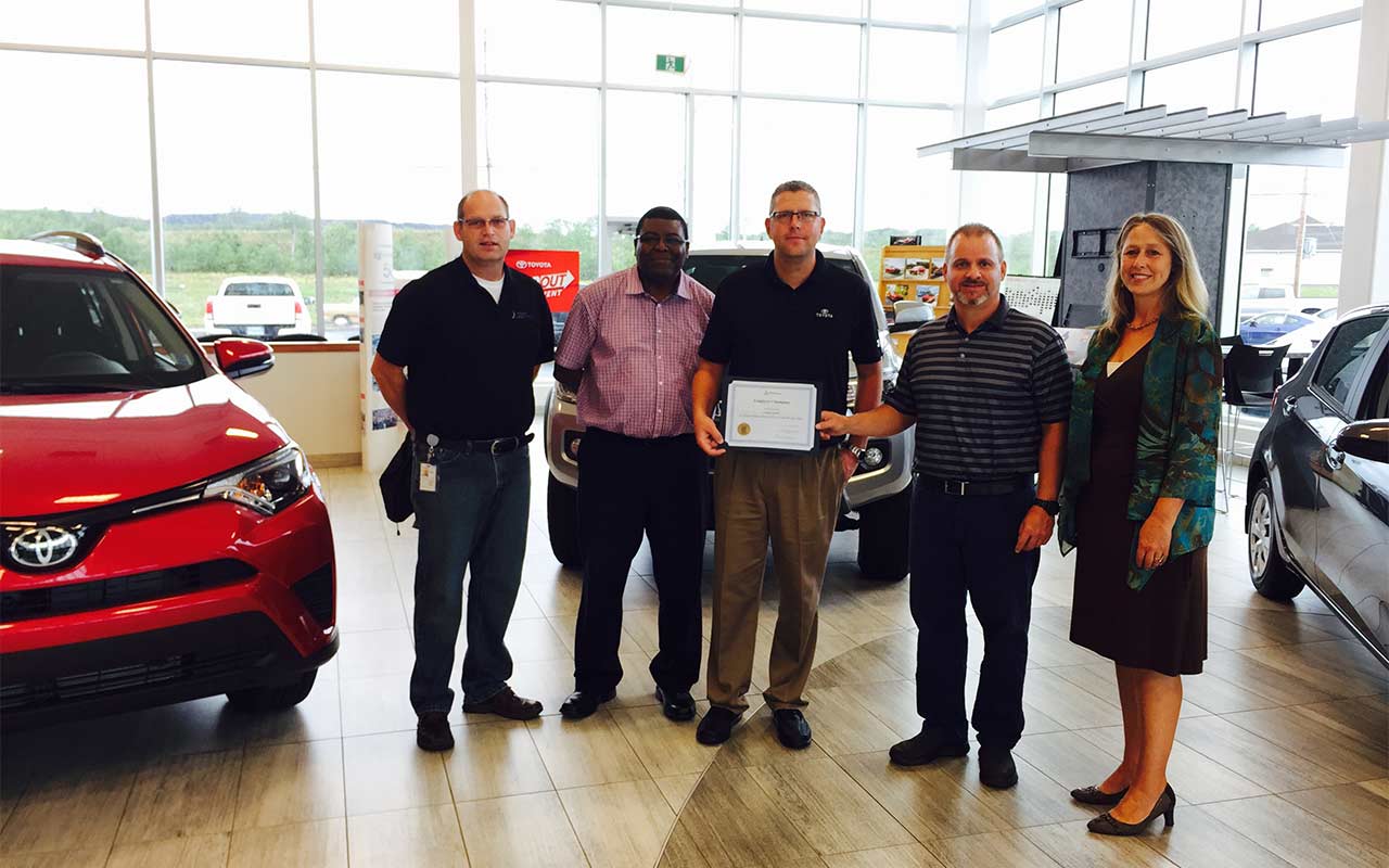 Employees of Anchor Motors gather around their Employer Champion award