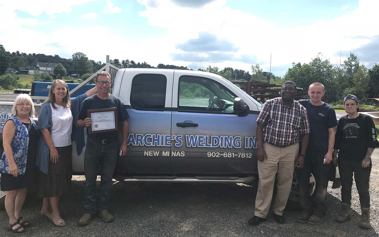 Employees of Archie's Welding gather around their Employer Champion award