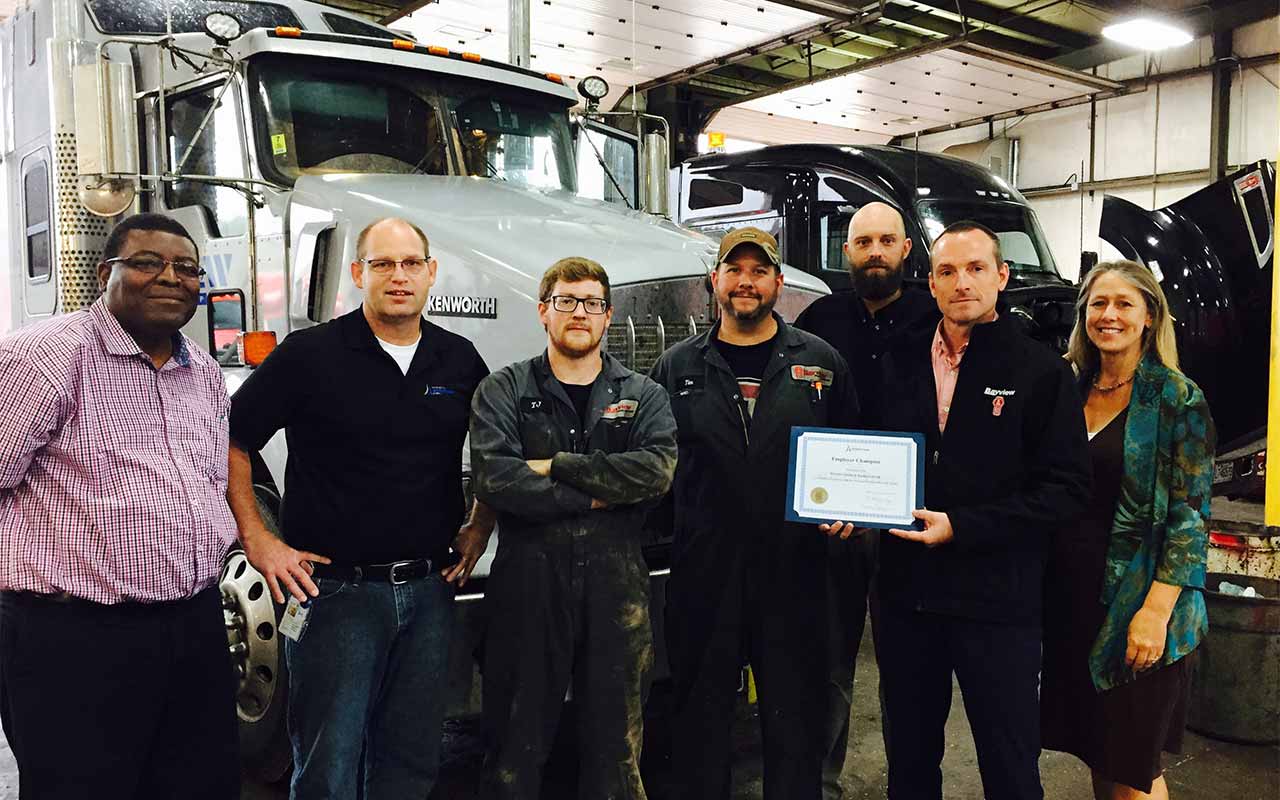 Employees of Bayview Trucks and Equipment gather around their Employer Champion award