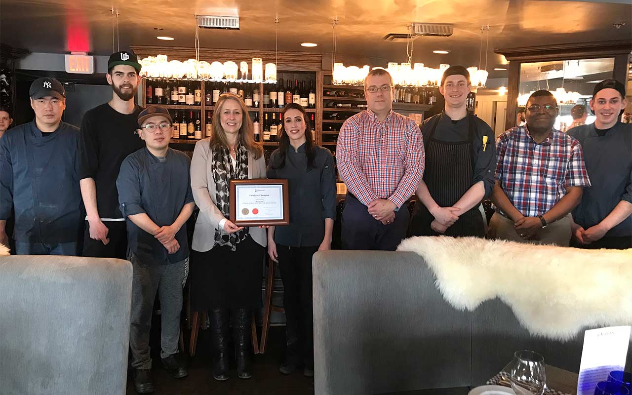 Seven employees of Halifax's The Bicycle Thief pose for a photo holding their Employer Champion award