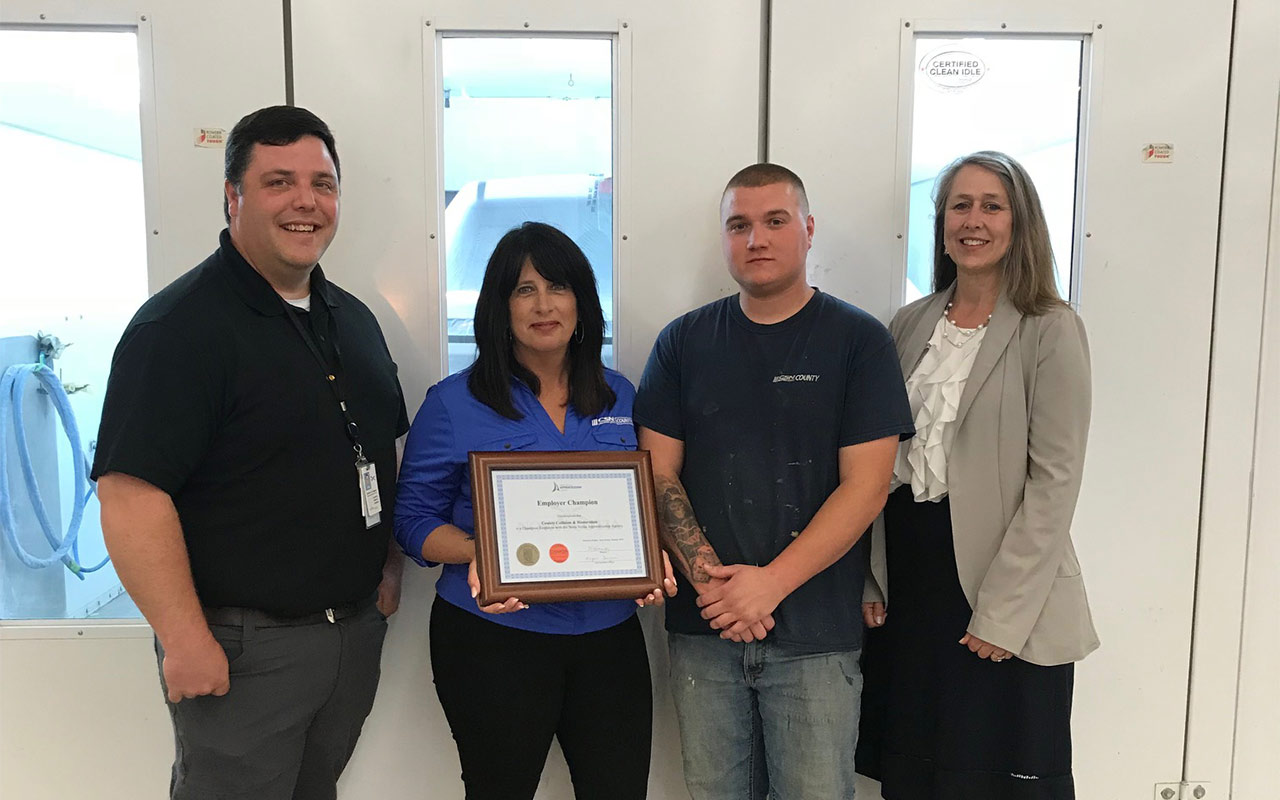 Employees of County Collision gather around their Employer Champion award