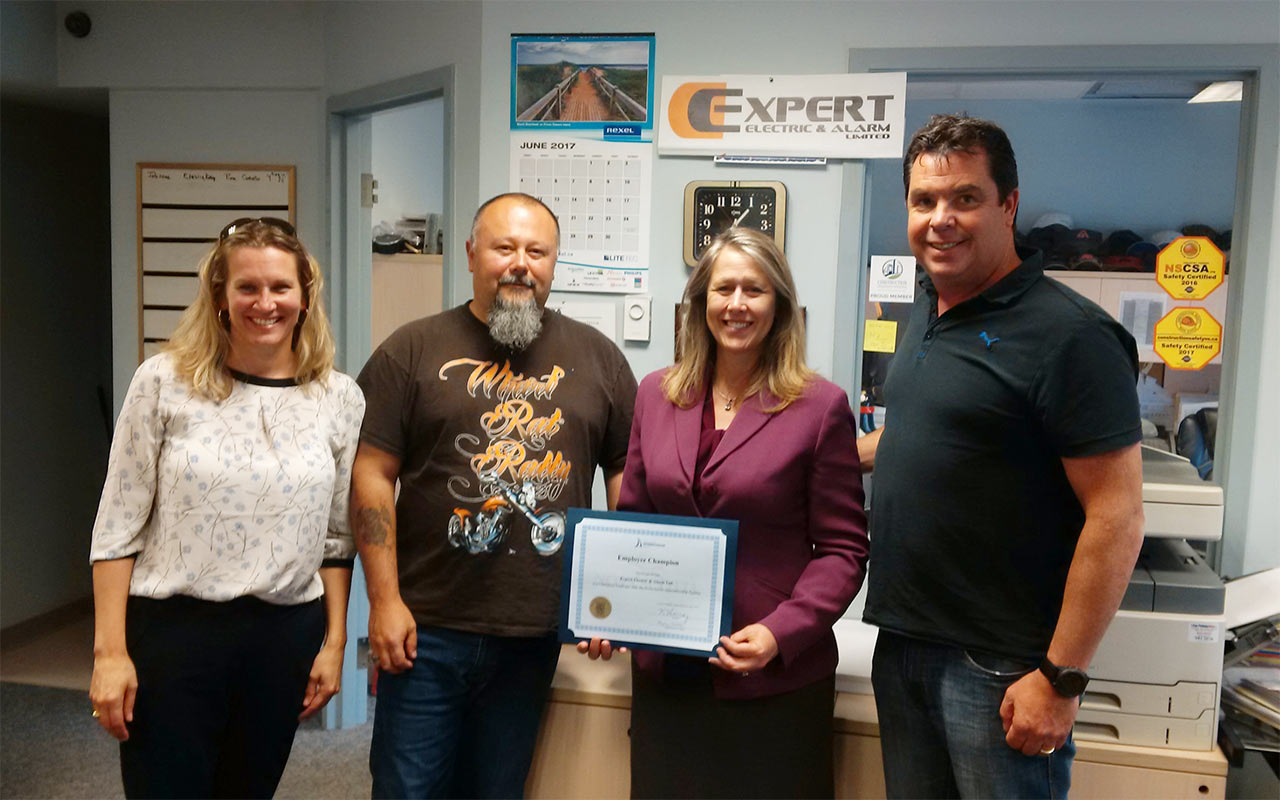 Employees of Expert Electric & Alarm gather around their Employer Champion award