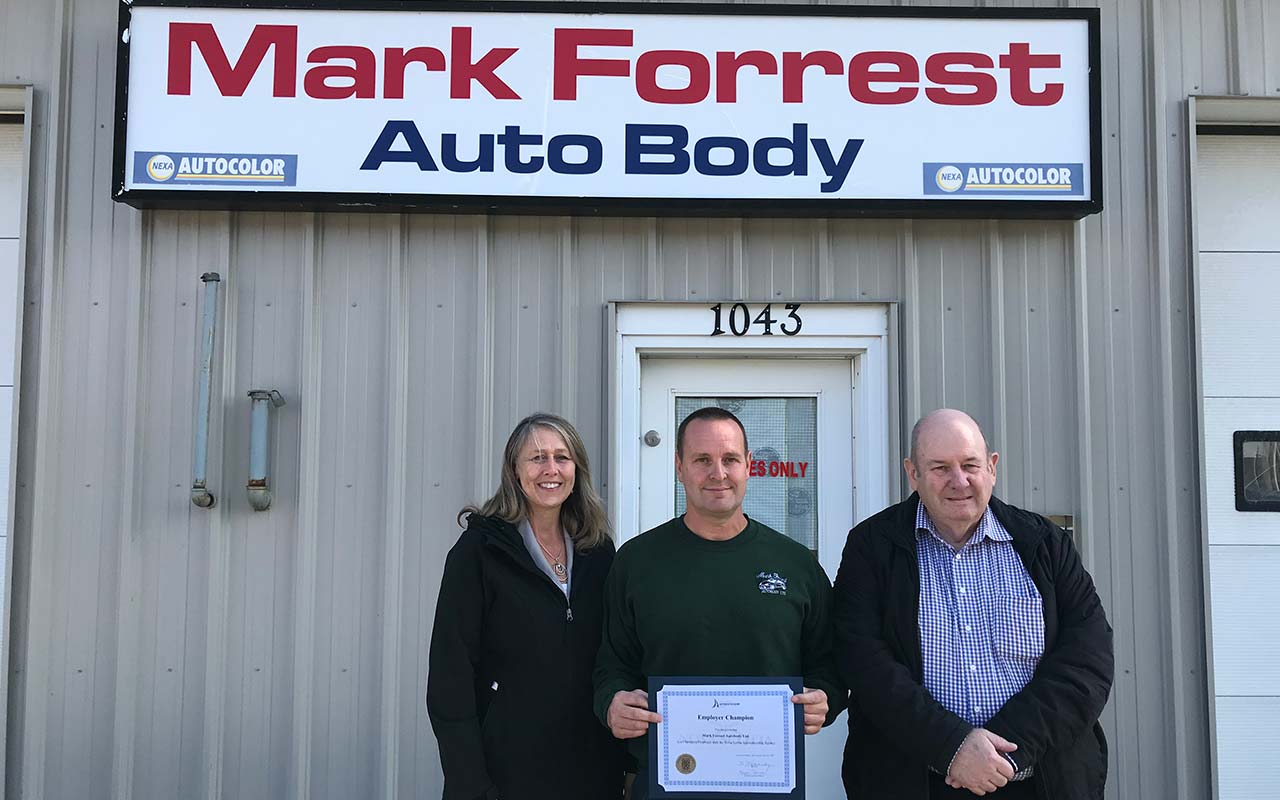 Employees of Mark Forrest Auto Body gather around their Employer Champion award