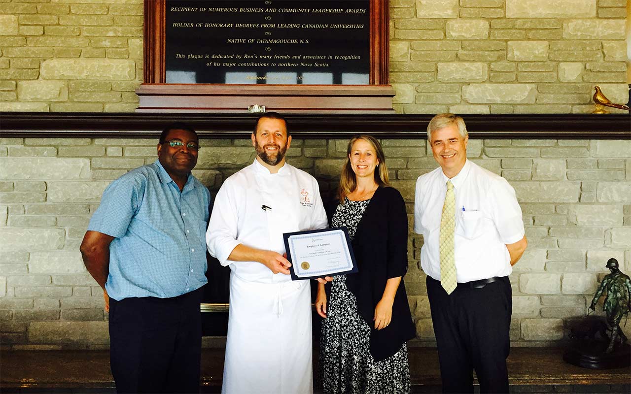 Employees of Fox Harb'r Resort gather around their Employer Champion award