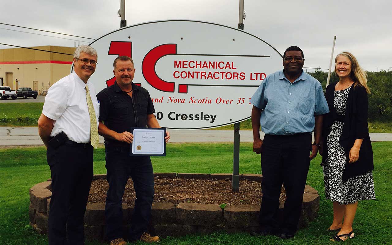 Employees of J.C. Mechanical Contractors gather around their Employer Champion award