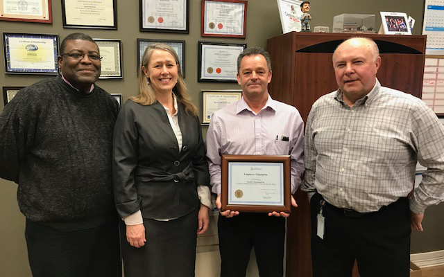 Employees of MacDow Mechanical gather around their Employer Champion award