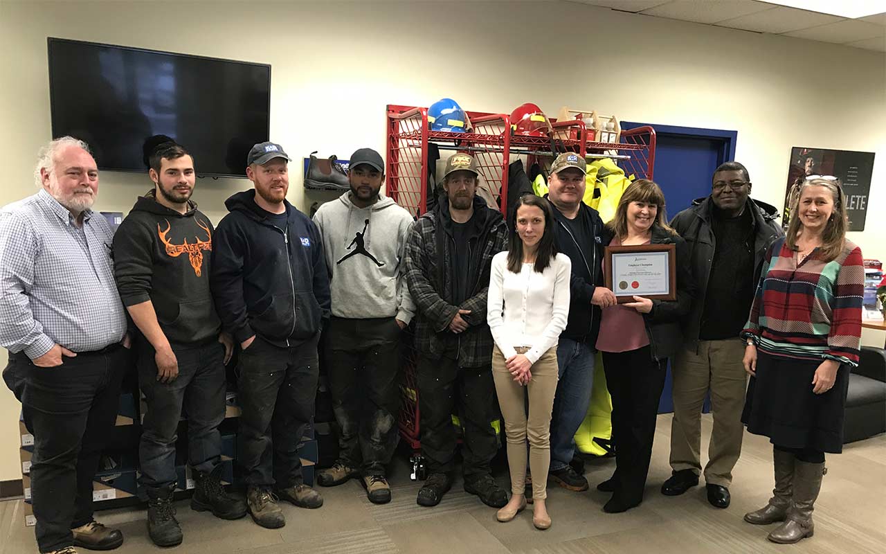 Employees of Marrimac gather around their Employer Champion award