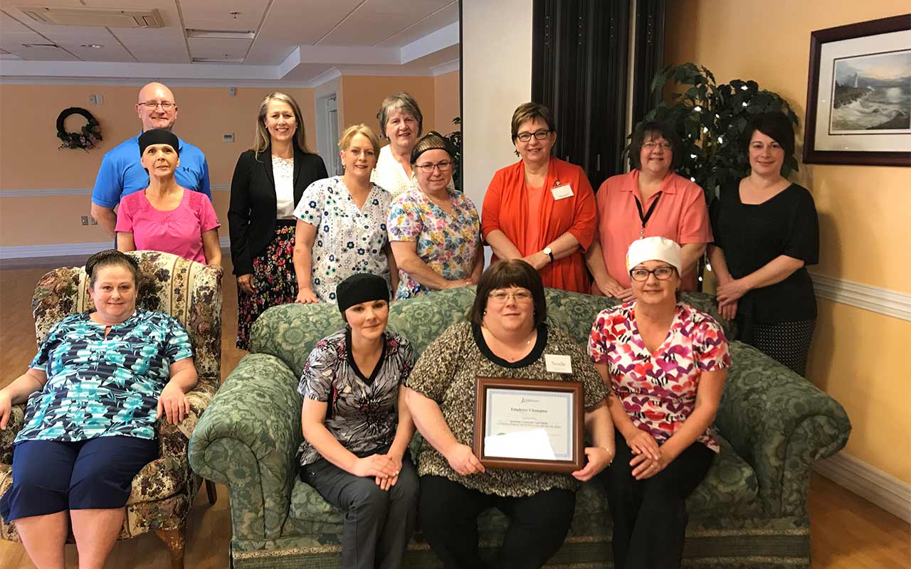 Employees of the Northside Community Guest Home gather around their Employer Champion award