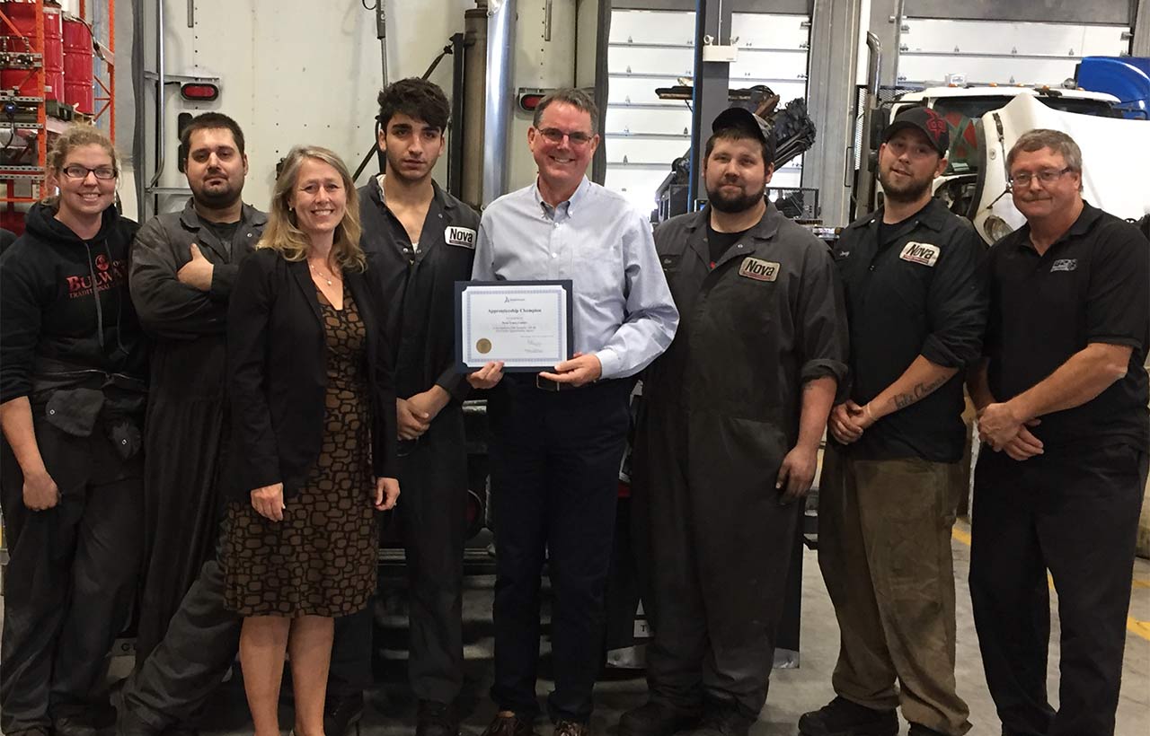 Employees of the Nova Truck Centers team gather around their Employer Champion award