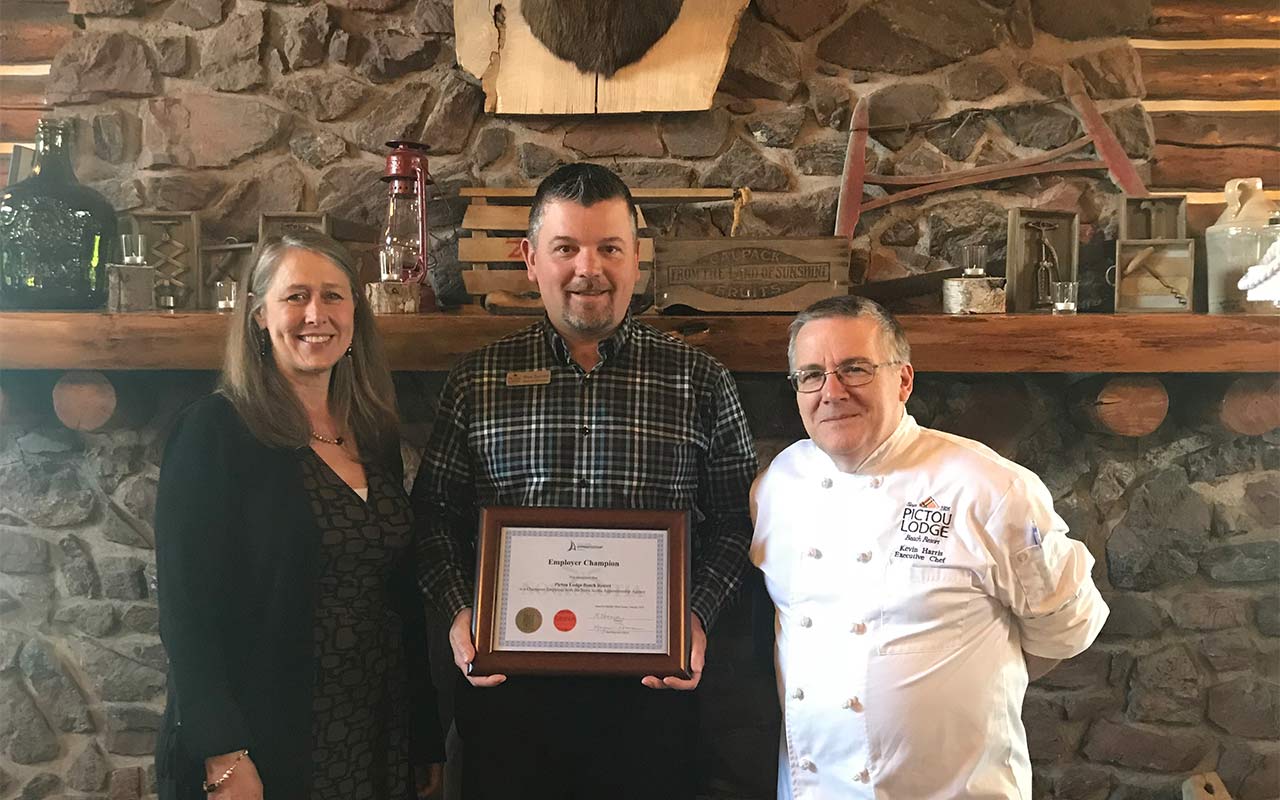 Employees of Pictou Lodge Beach Resort gather around their Employer Champion award