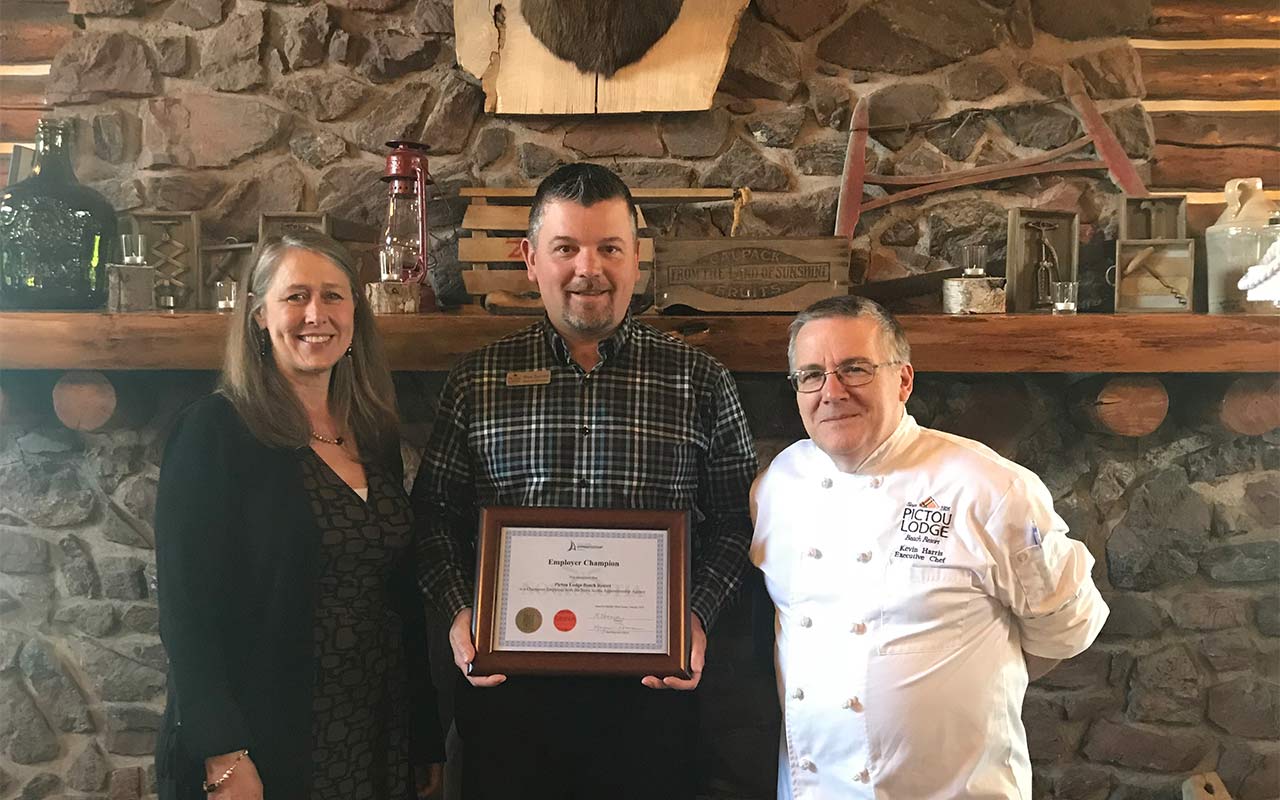 Employees of Pictou Lodge Beach Resort gather around their Employer Champion award