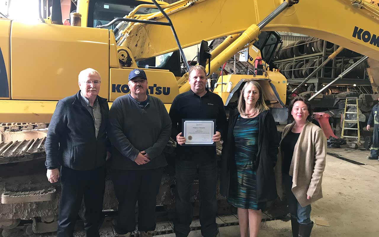 Employees of Zutphen Equipment gather around their Employer Champion award