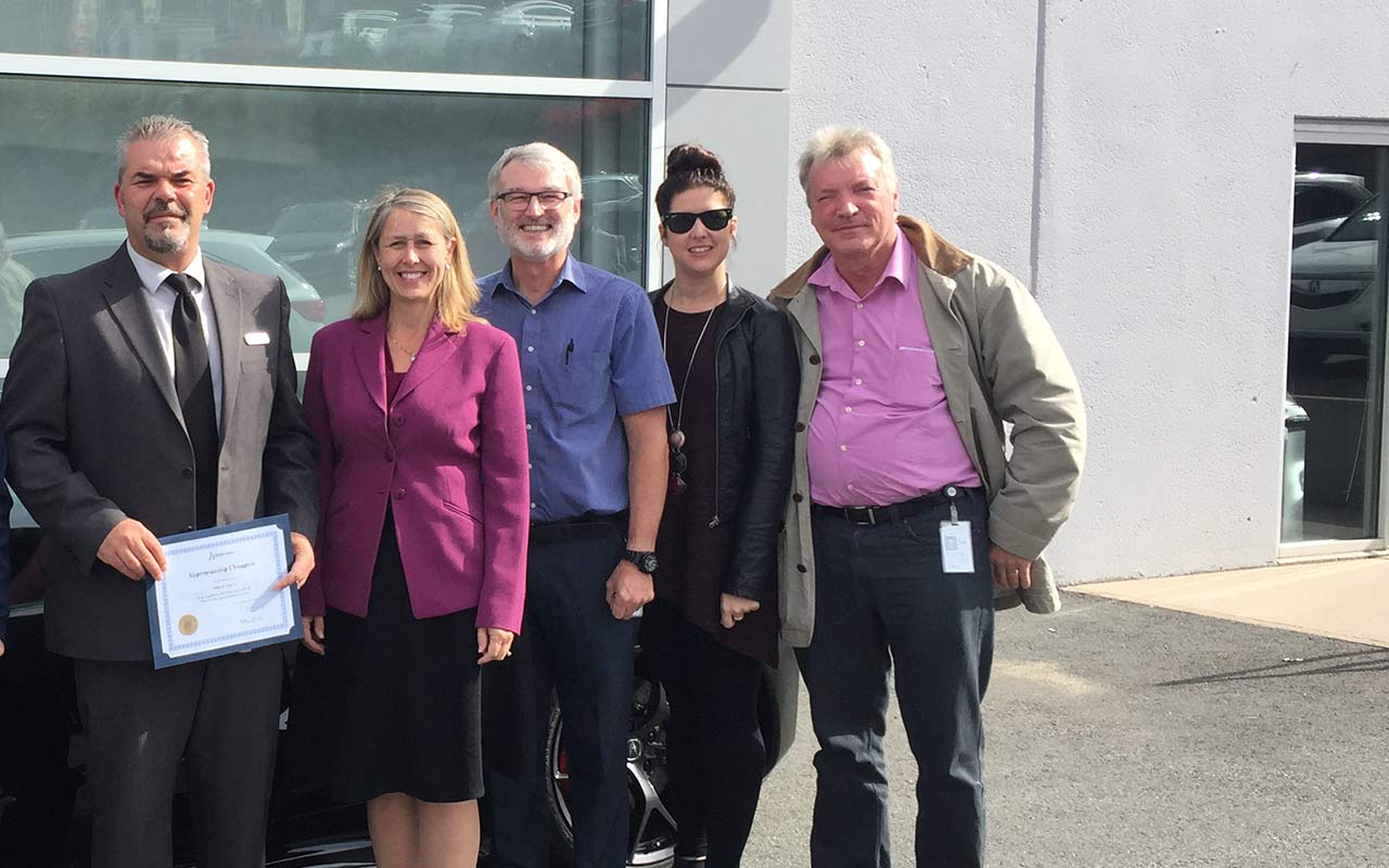 Employees of Atlantic Acura gather around their Employer Champion award