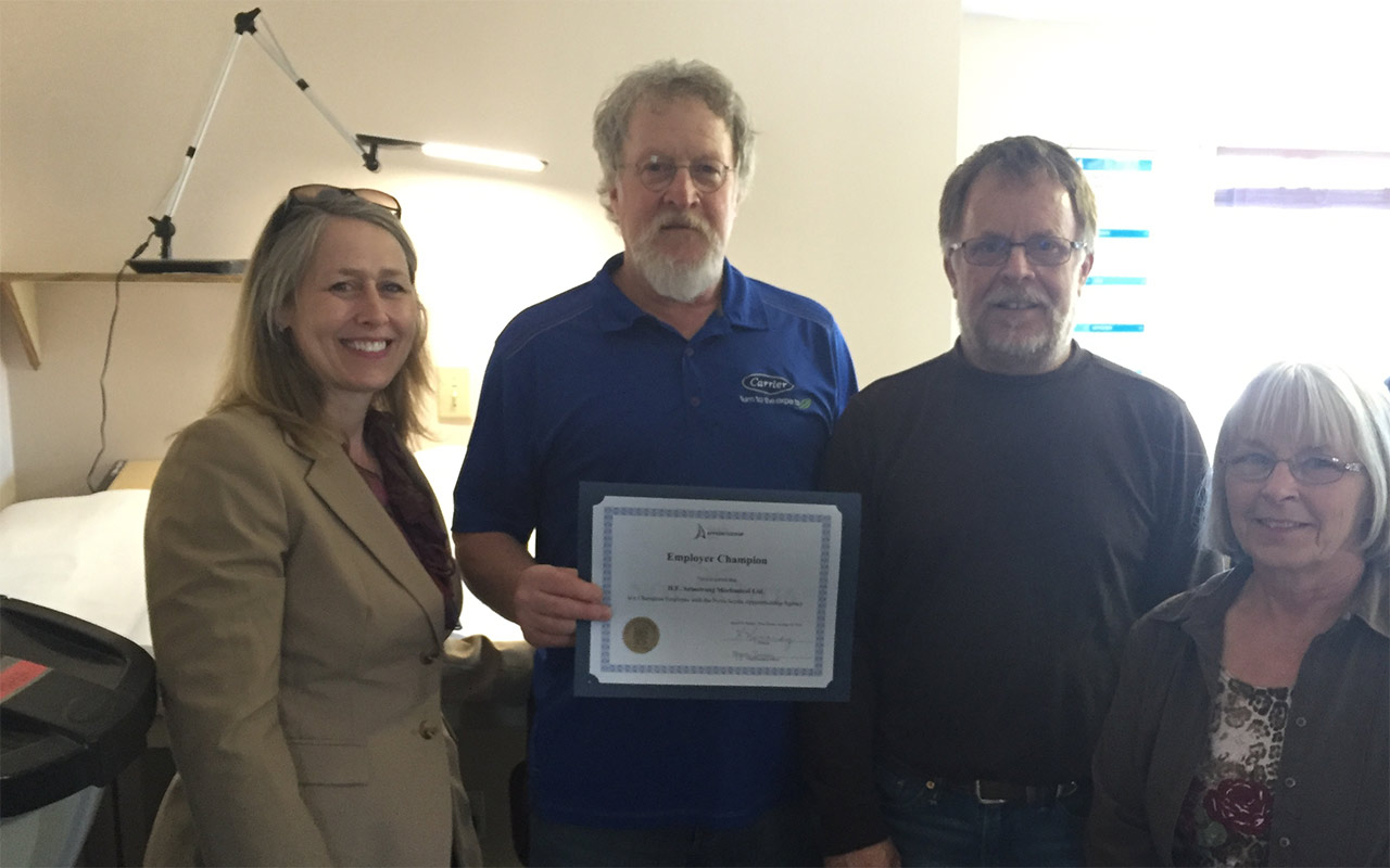 Employees of H. E. Armstrong gather around their Employer Champion award