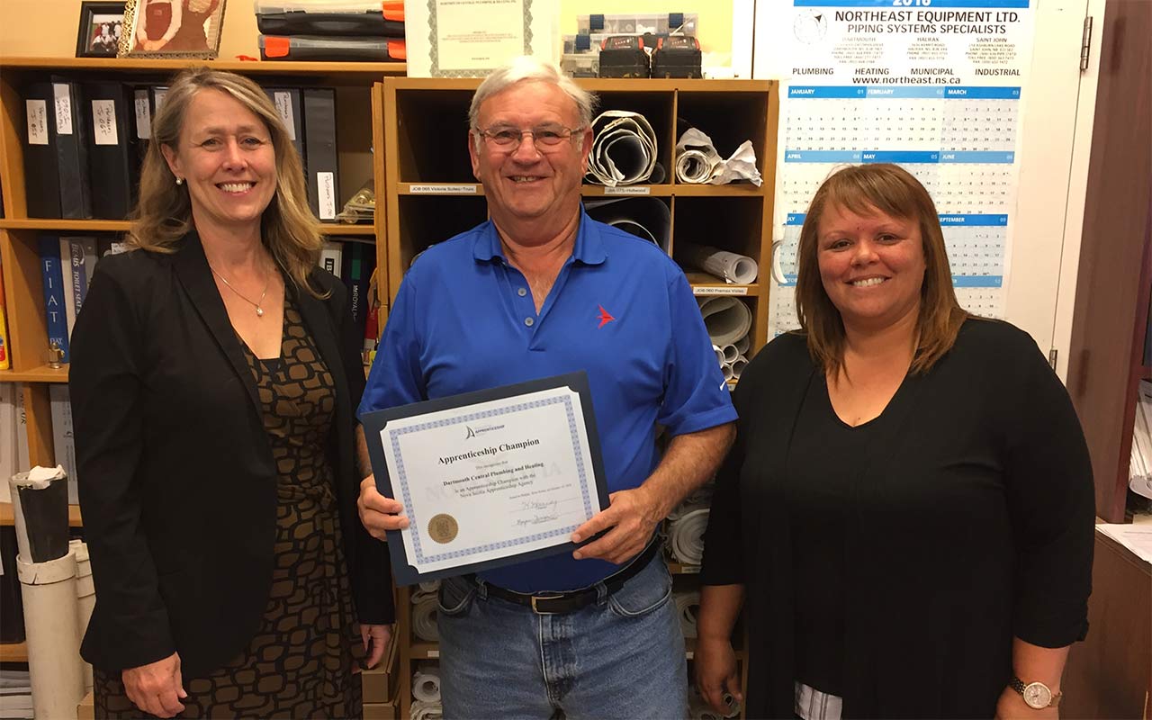 Employees of Central Plumbing and Heating gather around their Employer Champion award