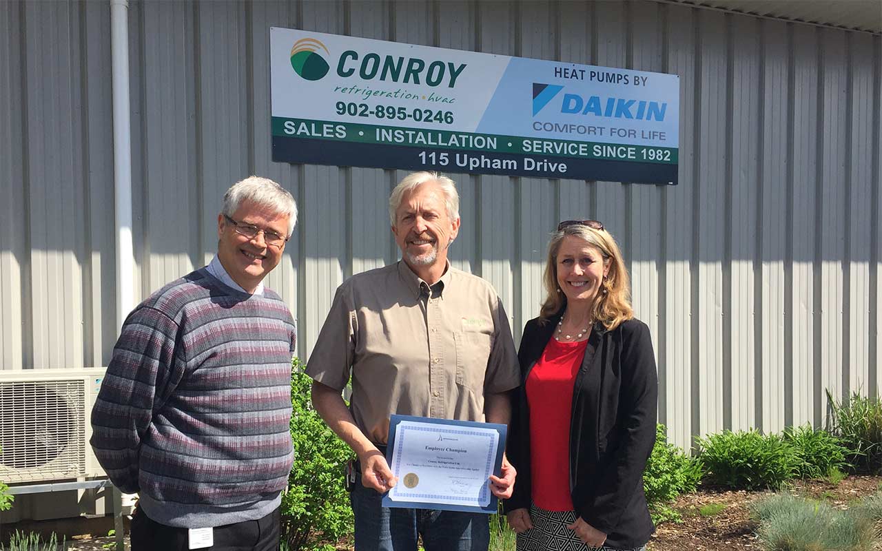 Employees of MacLeod's Fuels gather around their Employer Champion award