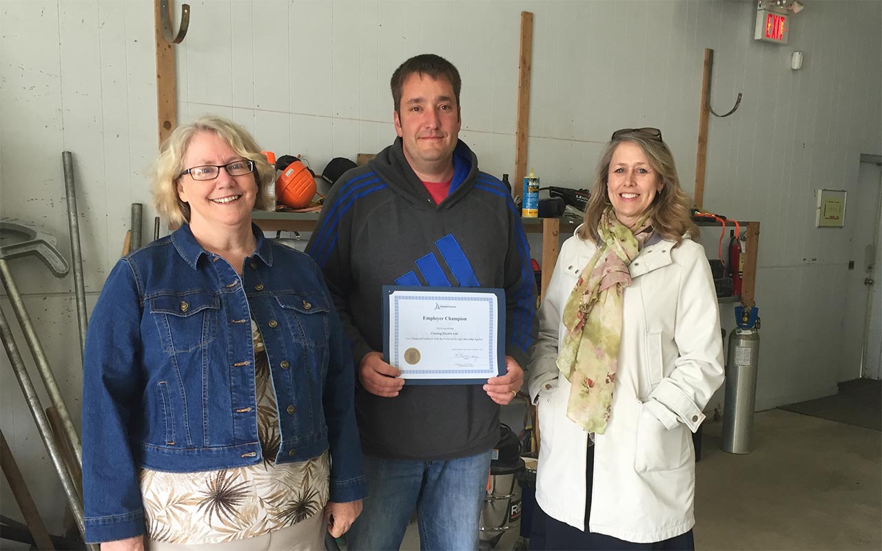 Employees of Corning Electric gather around their Employer Champion award