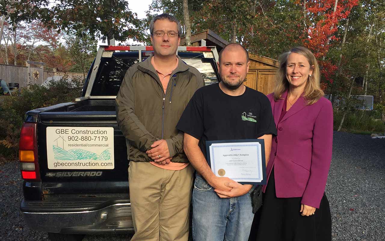 Employees of GBE Construction gather around their Employer Champion award