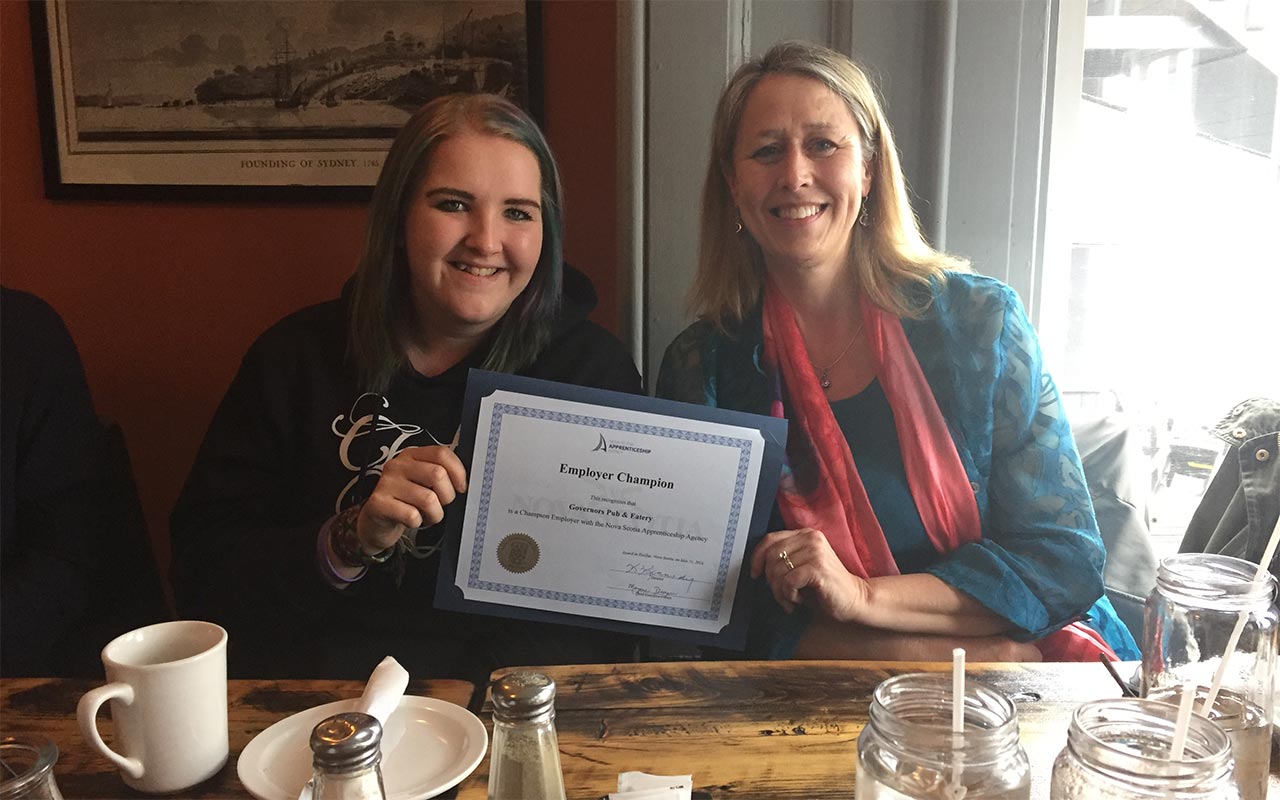 Employees of Governors Pub and Eatery gather around their Employer Champion award