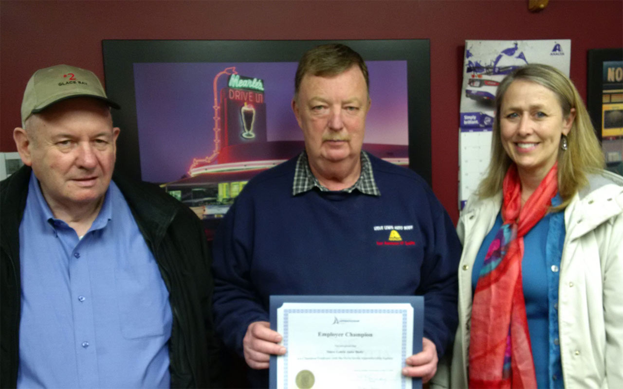 Employees of Steve Lewis Autobody gather around their Employer Champion award