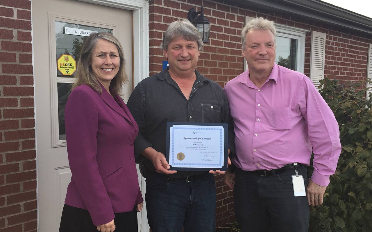 Employees of T.J.'s Electric gather around their Employer Champion award