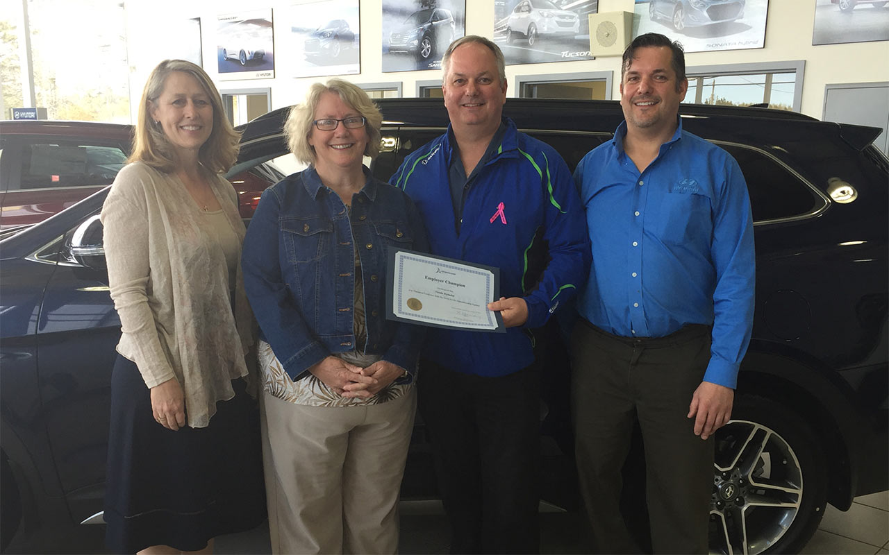 Employees of Thistle Hyundai gather around their Employer Champion award