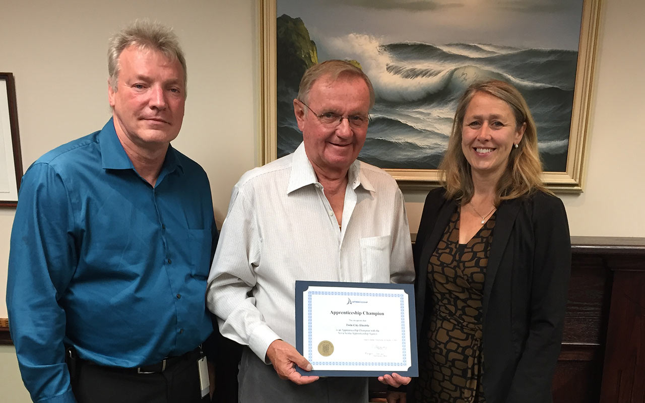 Employees of Twin City Electric gather around their Employer Champion award