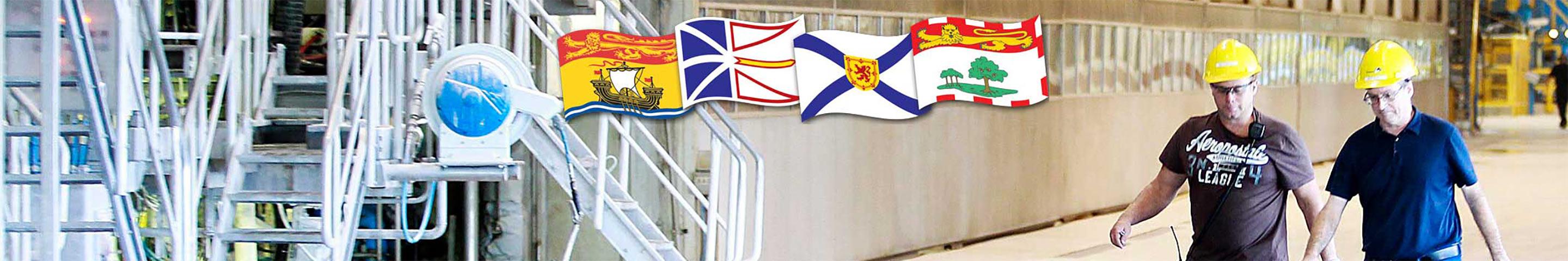 Two men wearing hard hats walking through a building with Nova Scotia flags in the background.